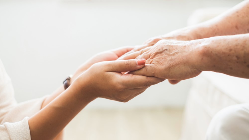 Someone holding an older persons hands
