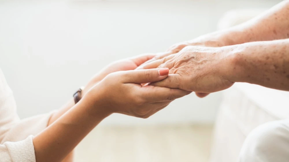Someone holding an older persons hands